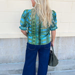 [Entro] Willow Embroidered Blouse featuring a green and light blue geometric pattern, V-neckline, puff sleeves, dark green trim, and embroidered details.