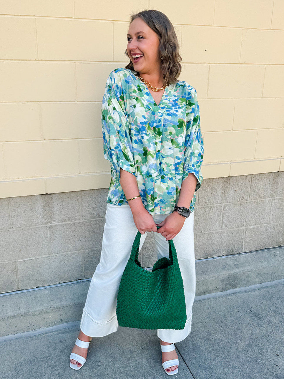 Loose-fit blouse with V-neckline and 3/4 sleeves in a pink, orange, and purple floral tie-dye print, styled for an effortless, vibrant look.