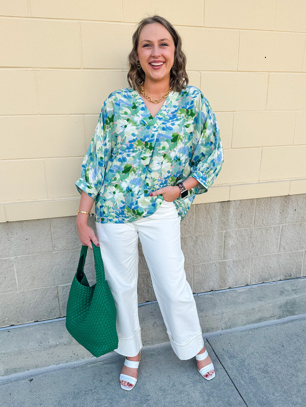 Loose-fit blouse with V-neckline and 3/4 sleeves in a pink, orange, and purple floral tie-dye print, styled for an effortless, vibrant look.