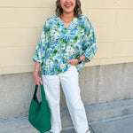 Loose-fit blouse with V-neckline and 3/4 sleeves in a pink, orange, and purple floral tie-dye print, styled for an effortless, vibrant look.