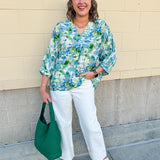 Loose-fit blouse with V-neckline and 3/4 sleeves in a pink, orange, and purple floral tie-dye print, styled for an effortless, vibrant look.