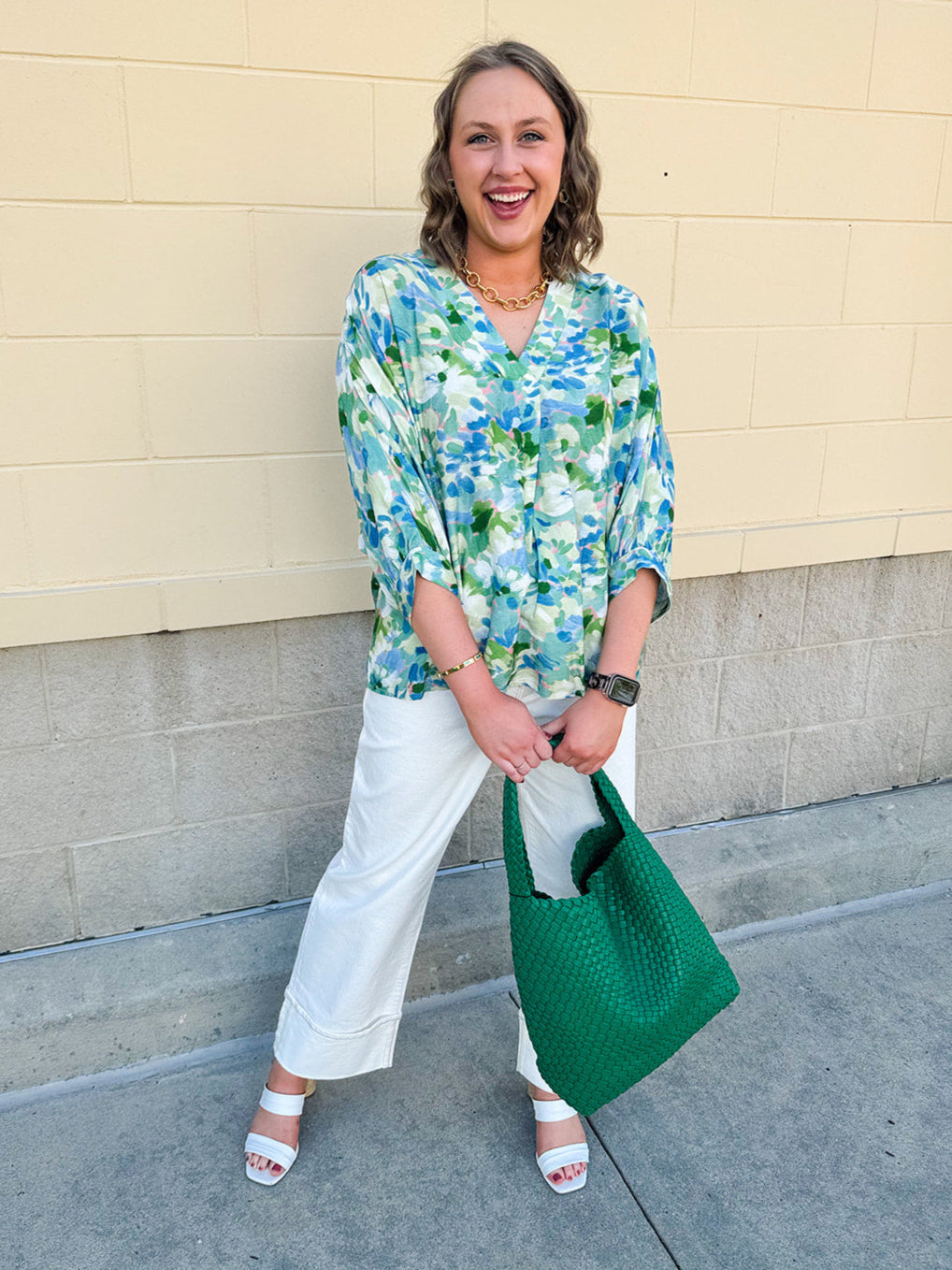Loose-fit blouse with V-neckline and 3/4 sleeves in a pink, orange, and purple floral tie-dye print, styled for an effortless, vibrant look.