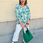 Loose-fit blouse with V-neckline and 3/4 sleeves in a pink, orange, and purple floral tie-dye print, styled for an effortless, vibrant look.