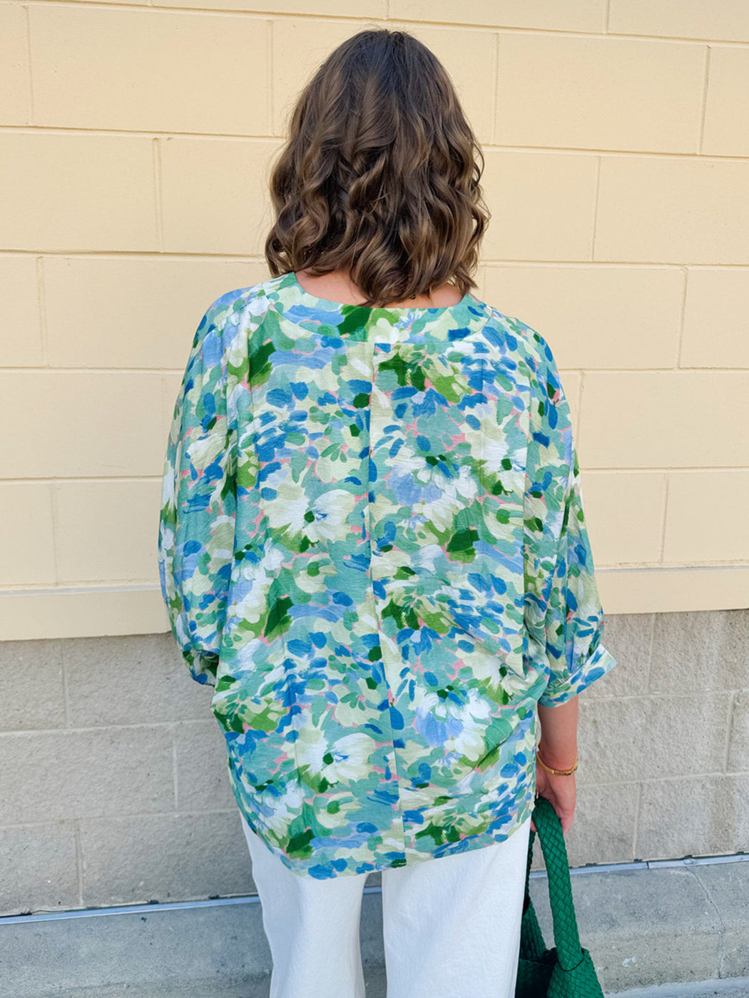 Loose-fit blouse with V-neckline and 3/4 sleeves in a pink, orange, and purple floral tie-dye print, styled for an effortless, vibrant look.