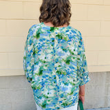 Loose-fit blouse with V-neckline and 3/4 sleeves in a pink, orange, and purple floral tie-dye print, styled for an effortless, vibrant look.