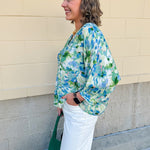 Loose-fit blouse with V-neckline and 3/4 sleeves in a pink, orange, and purple floral tie-dye print, styled for an effortless, vibrant look.