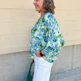 Loose-fit blouse with V-neckline and 3/4 sleeves in a pink, orange, and purple floral tie-dye print, styled for an effortless, vibrant look.
