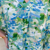 Loose-fit blouse with V-neckline and 3/4 sleeves in a pink, orange, and purple floral tie-dye print, styled for an effortless, vibrant look.