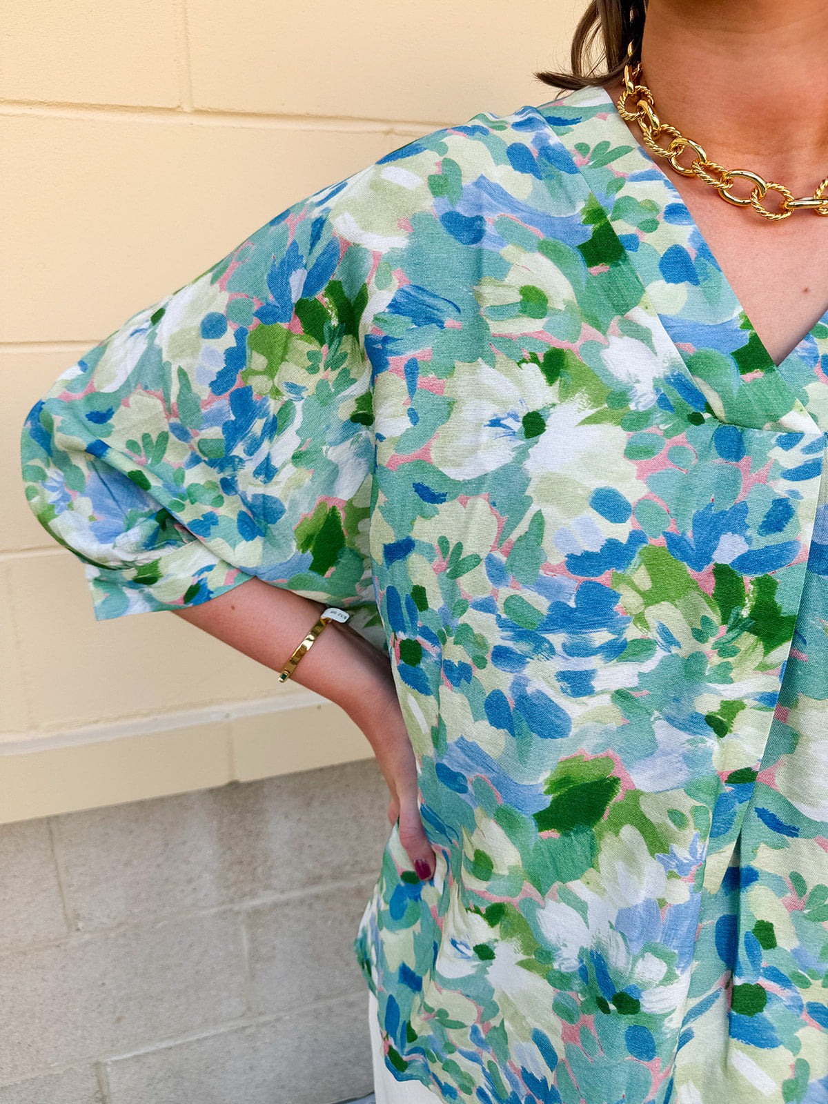 Loose-fit blouse with V-neckline and 3/4 sleeves in a pink, orange, and purple floral tie-dye print, styled for an effortless, vibrant look.