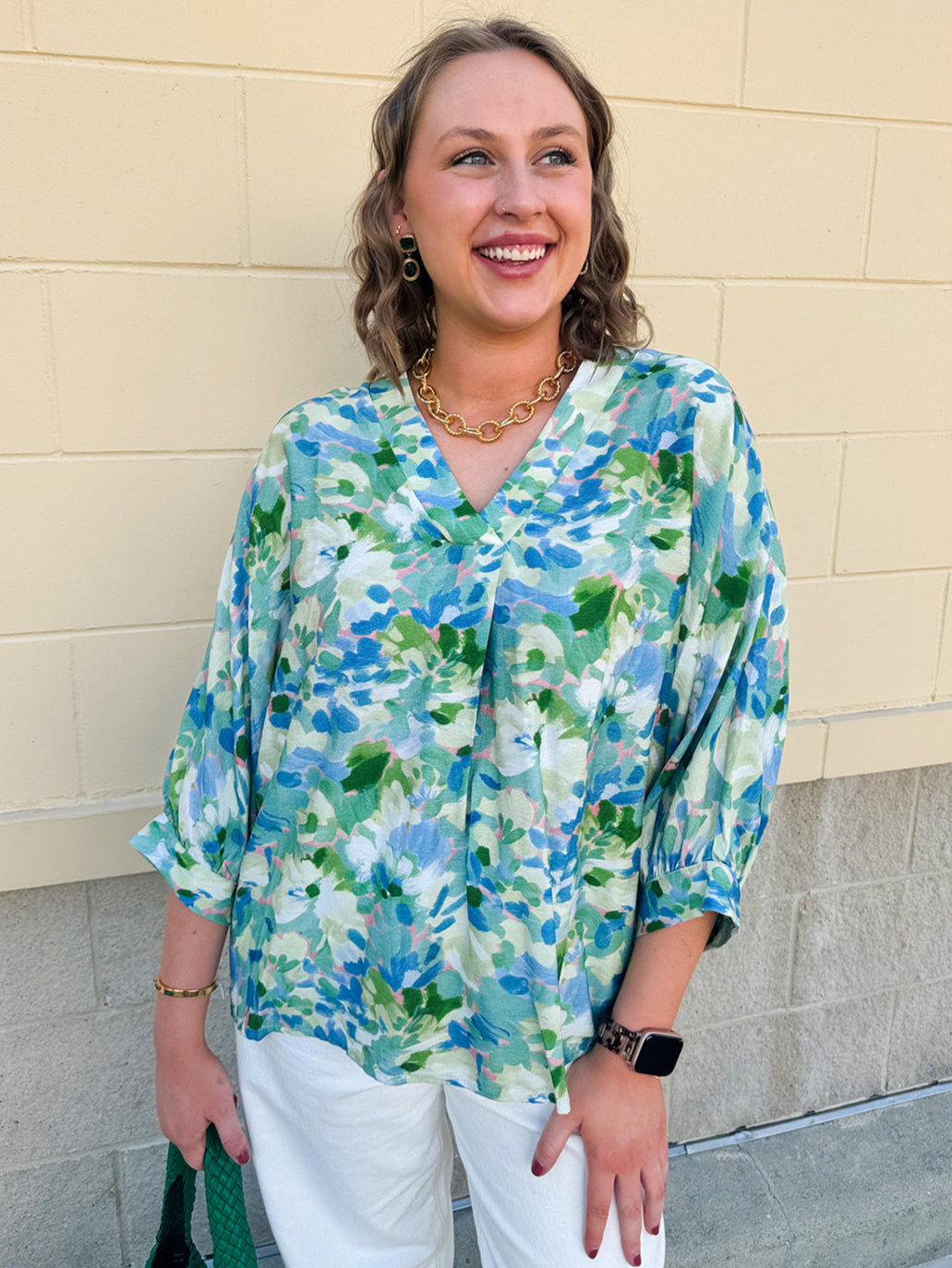 Loose-fit blouse with V-neckline and 3/4 sleeves in a pink, orange, and purple floral tie-dye print, styled for an effortless, vibrant look.