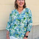 Loose-fit blouse with V-neckline and 3/4 sleeves in a pink, orange, and purple floral tie-dye print, styled for an effortless, vibrant look.