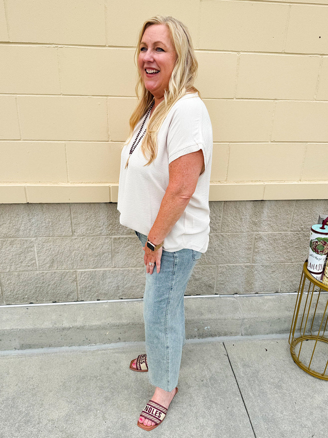Lightweight oatmeal V-neck top with cap sleeves, styled casually for Gameday. The neutral tone and relaxed fit offer a versatile, polished look.