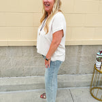 Lightweight oatmeal V-neck top with cap sleeves, styled casually for Gameday. The neutral tone and relaxed fit offer a versatile, polished look.