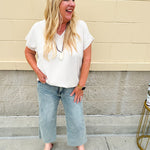 Lightweight oatmeal V-neck top with cap sleeves, styled casually for Gameday. The neutral tone and relaxed fit offer a versatile, polished look.