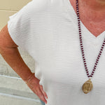 Lightweight oatmeal V-neck top with cap sleeves, styled casually for Gameday. The neutral tone and relaxed fit offer a versatile, polished look.