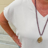 Lightweight oatmeal V-neck top with cap sleeves, styled casually for Gameday. The neutral tone and relaxed fit offer a versatile, polished look.