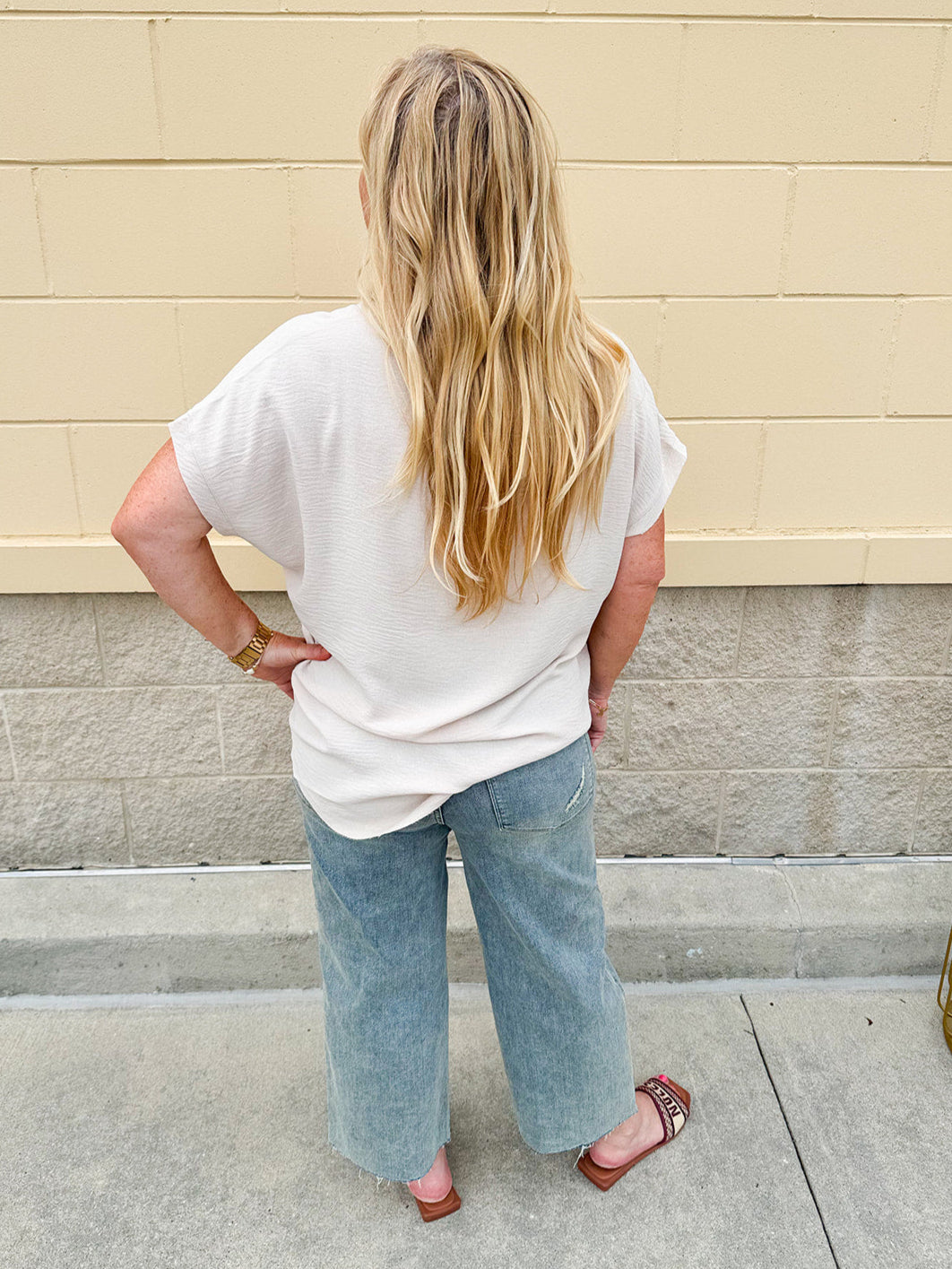Lightweight oatmeal V-neck top with cap sleeves, styled casually for Gameday. The neutral tone and relaxed fit offer a versatile, polished look.