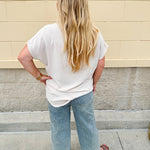 Lightweight oatmeal V-neck top with cap sleeves, styled casually for Gameday. The neutral tone and relaxed fit offer a versatile, polished look.