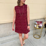 Sleeveless mini dress in rich garnet with 3D floral appliqué, scalloped embroidered hem, and side pockets. Elegant, textured, and perfect for fall or Gameday.