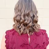 Sleeveless mini dress in rich garnet with 3D floral appliqué, scalloped embroidered hem, and side pockets. Elegant, textured, and perfect for fall or Gameday.
