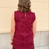 Sleeveless mini dress in rich garnet with 3D floral appliqué, scalloped embroidered hem, and side pockets. Elegant, textured, and perfect for fall or Gameday.