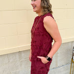 Sleeveless mini dress in rich garnet with 3D floral appliqué, scalloped embroidered hem, and side pockets. Elegant, textured, and perfect for fall or Gameday.