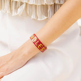 Garnet resin cuff bracelet with gold glitter NOLES lettering.