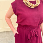 Garnet short-sleeve jumpsuit with elastic waist, front tie, high scoop neckline, and side pockets. Sporty, flattering, and perfect for Gameday style.