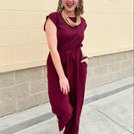 Garnet short-sleeve jumpsuit with elastic waist, front tie, high scoop neckline, and side pockets. Sporty, flattering, and perfect for Gameday style.