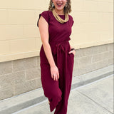 Garnet short-sleeve jumpsuit with elastic waist, front tie, high scoop neckline, and side pockets. Sporty, flattering, and perfect for Gameday style.