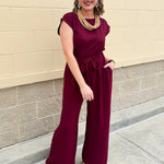 Garnet short-sleeve jumpsuit with elastic waist, front tie, high scoop neckline, and side pockets. Sporty, flattering, and perfect for Gameday style.