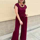 Garnet short-sleeve jumpsuit with elastic waist, front tie, high scoop neckline, and side pockets. Sporty, flattering, and perfect for Gameday style.