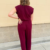 Garnet short-sleeve jumpsuit with elastic waist, front tie, high scoop neckline, and side pockets. Sporty, flattering, and perfect for Gameday style.