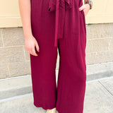 Garnet short-sleeve jumpsuit with elastic waist, front tie, high scoop neckline, and side pockets. Sporty, flattering, and perfect for Gameday style.