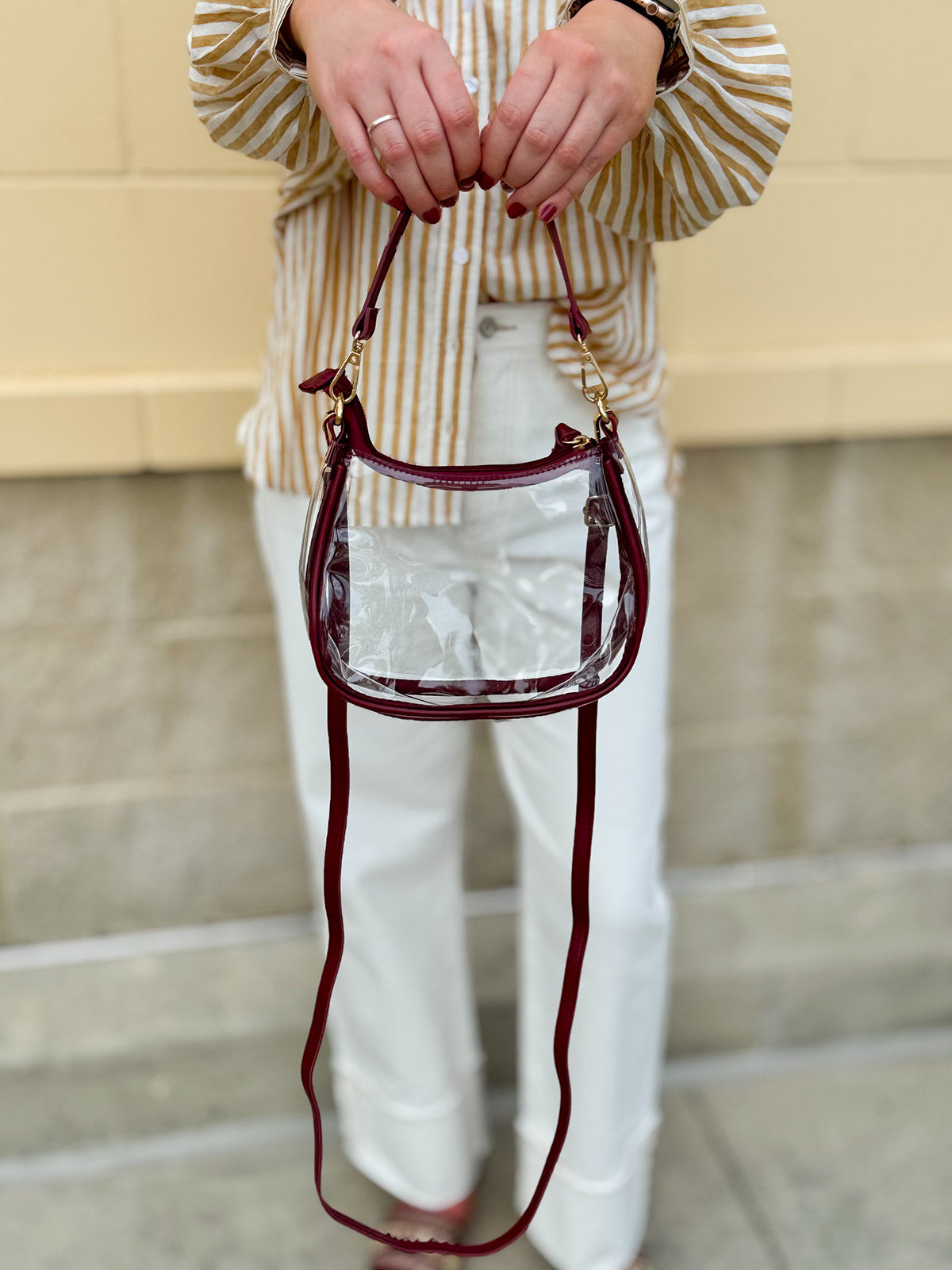Clear crossbody stadium bag with garnet straps and gold hardware, perfect for stylish game day looks.