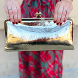 Gold Isabella Clutch featuring a sleek vegan leather design with clasp closure and structured silhouette.