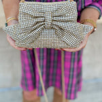 Gold gemstone crossbody bag with bow detail and metal chain strap.