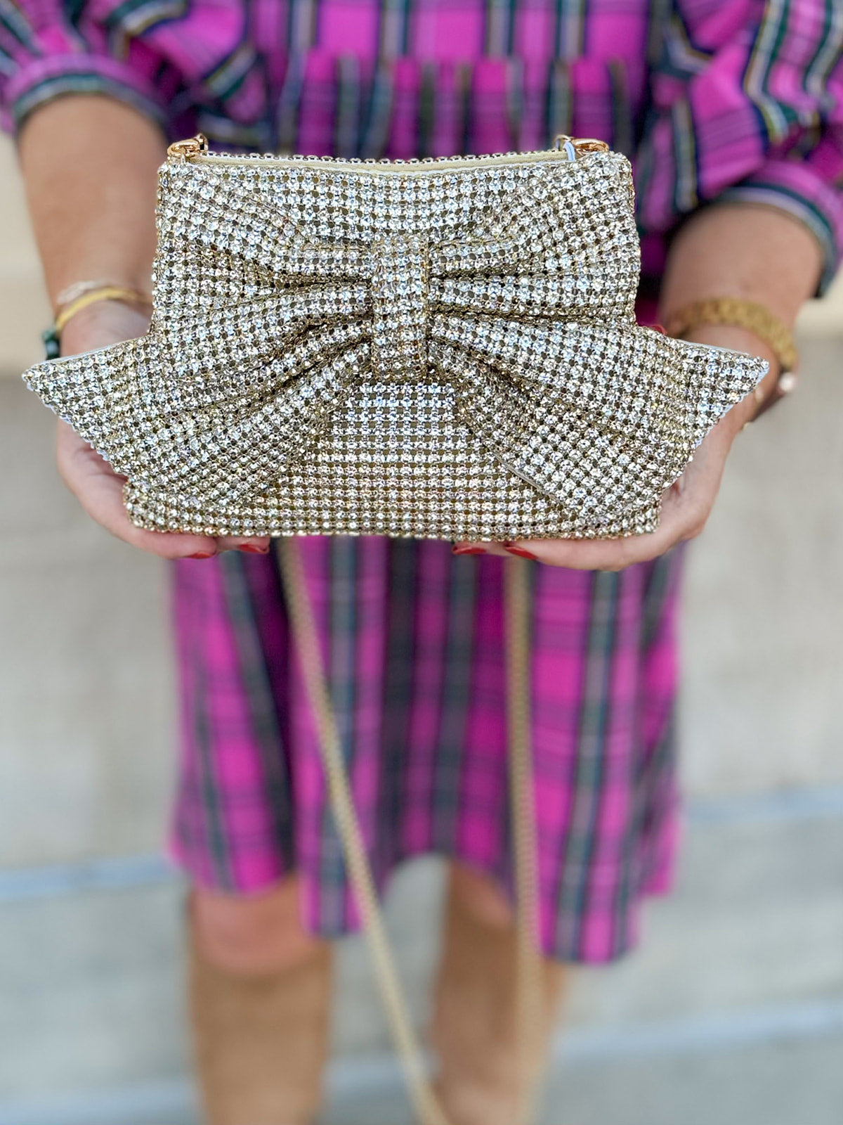 Gold gemstone crossbody bag with bow detail and metal chain strap.