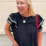 Black woven top with round neckline, ruffle sleeves, and flowy relaxed silhouette.