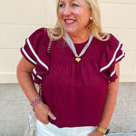 Garnet woven top with round neckline, ruffle sleeves, and flowy relaxed silhouette.