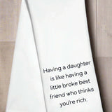 White kitchen towel with the phrase “Having a daughter is like having a little broke best friend who thinks you’re rich”