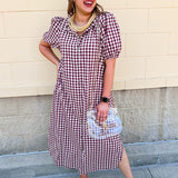 Dark red checkered midi dress with puff sleeves, a ruffled collar, button-down front, hidden side pockets, and a flowing midi-length silhouette.