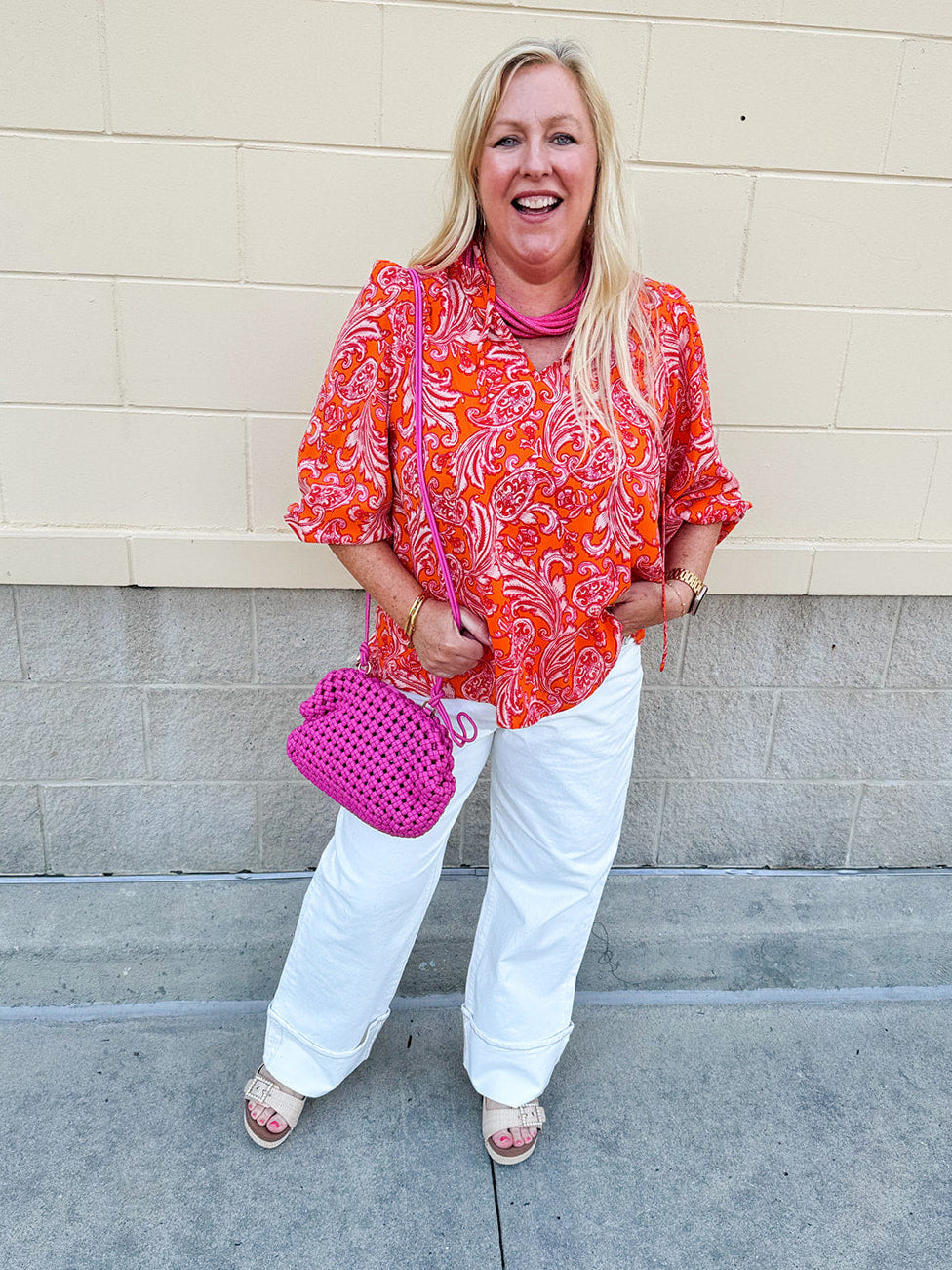 Pink and orange paisley print blouse with frilled tie neckline and three-quarter peasant sleeves against a neutral background