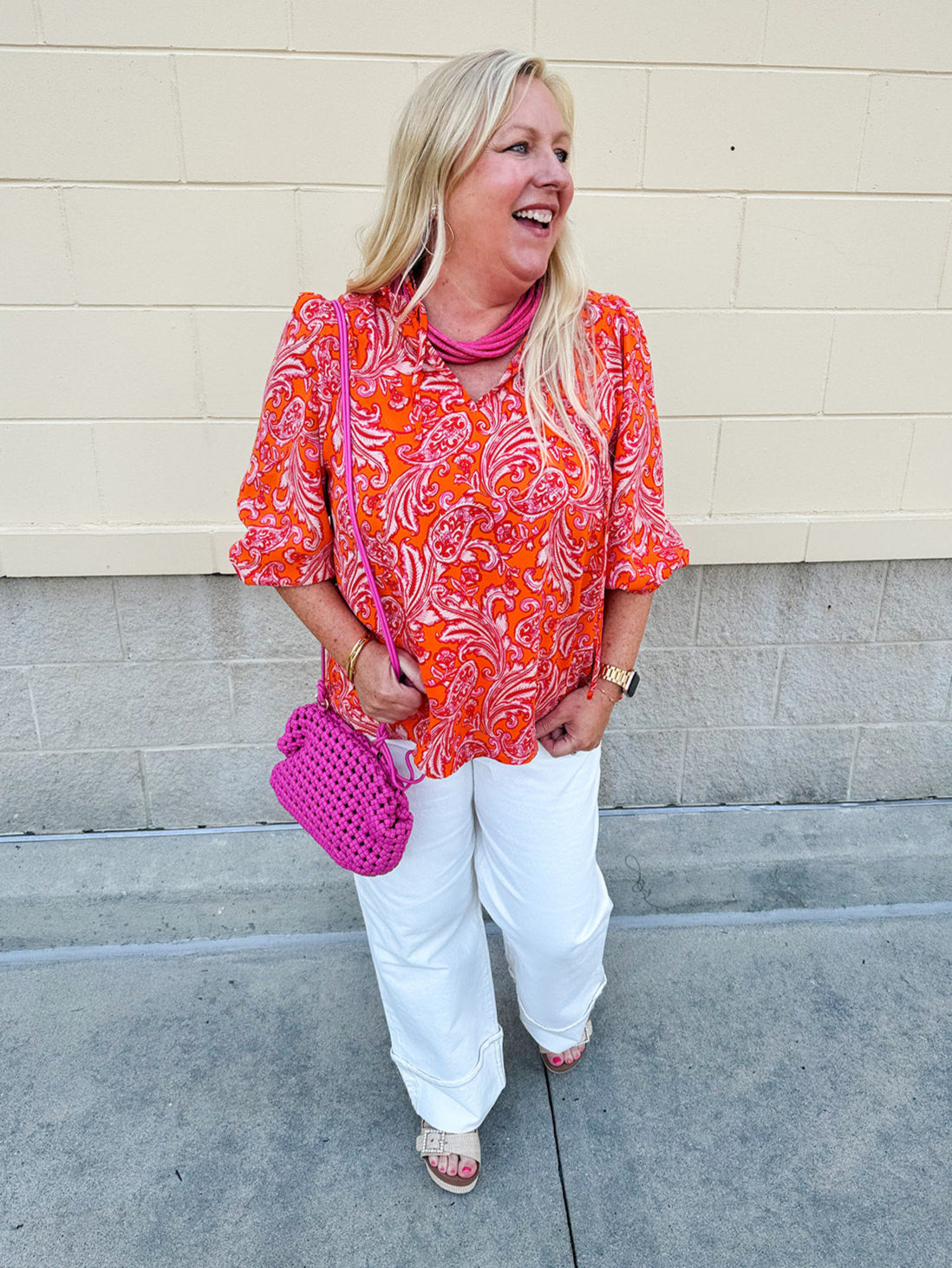 Pink and orange paisley print blouse with frilled tie neckline and three-quarter peasant sleeves against a neutral background