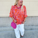 Pink and orange paisley print blouse with frilled tie neckline and three-quarter peasant sleeves against a neutral background
