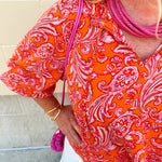 Pink and orange paisley print blouse with frilled tie neckline and three-quarter peasant sleeves against a neutral background