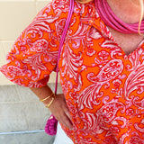 Pink and orange paisley print blouse with frilled tie neckline and three-quarter peasant sleeves against a neutral background