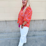 Pink and orange paisley print blouse with frilled tie neckline and three-quarter peasant sleeves against a neutral background