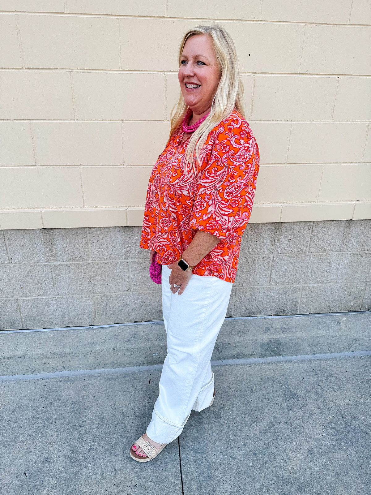 Pink and orange paisley print blouse with frilled tie neckline and three-quarter peasant sleeves against a neutral background