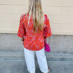 Pink and orange paisley print blouse with frilled tie neckline and three-quarter peasant sleeves against a neutral background